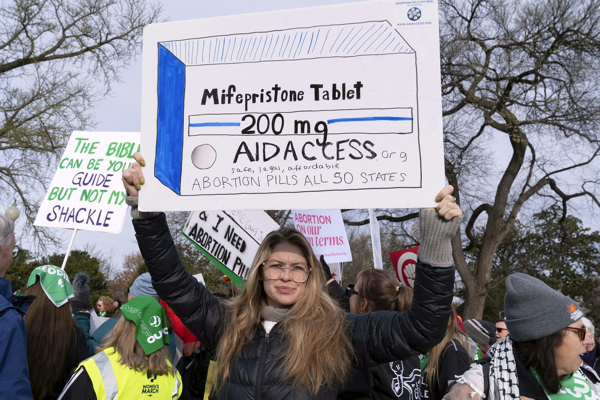 a woman holds a sign supporting access to abortion pills at a protest rally