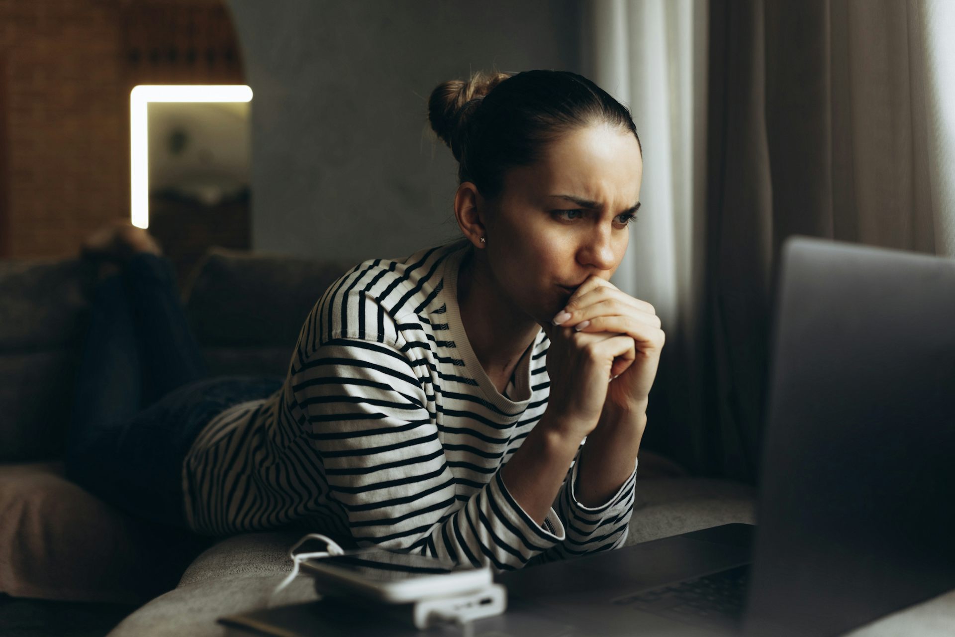 Stressed person looking at laptop with elbows leaning on surface and clasped hands over mouth