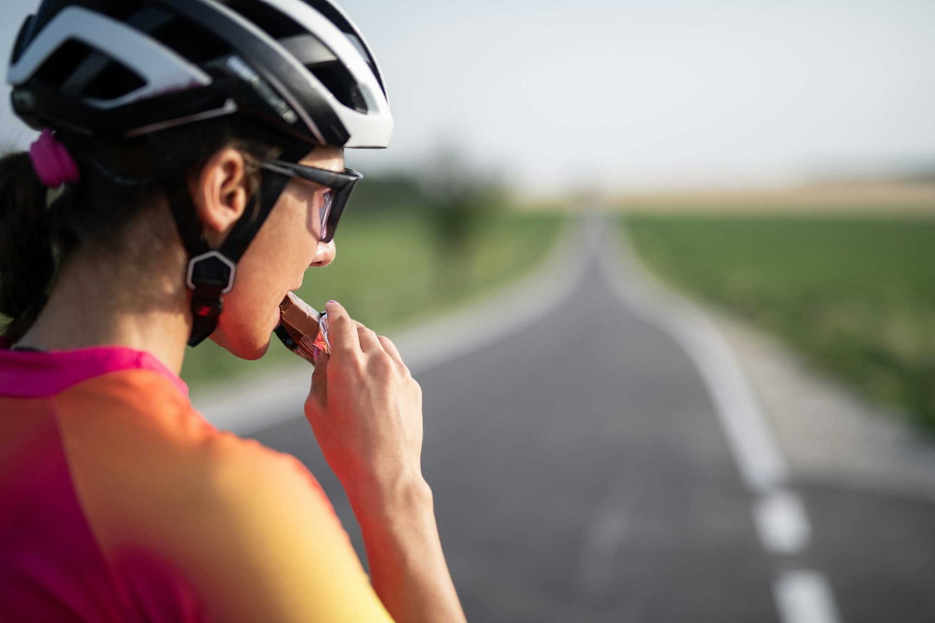 Cyclist eating protein bar, looking out at the road