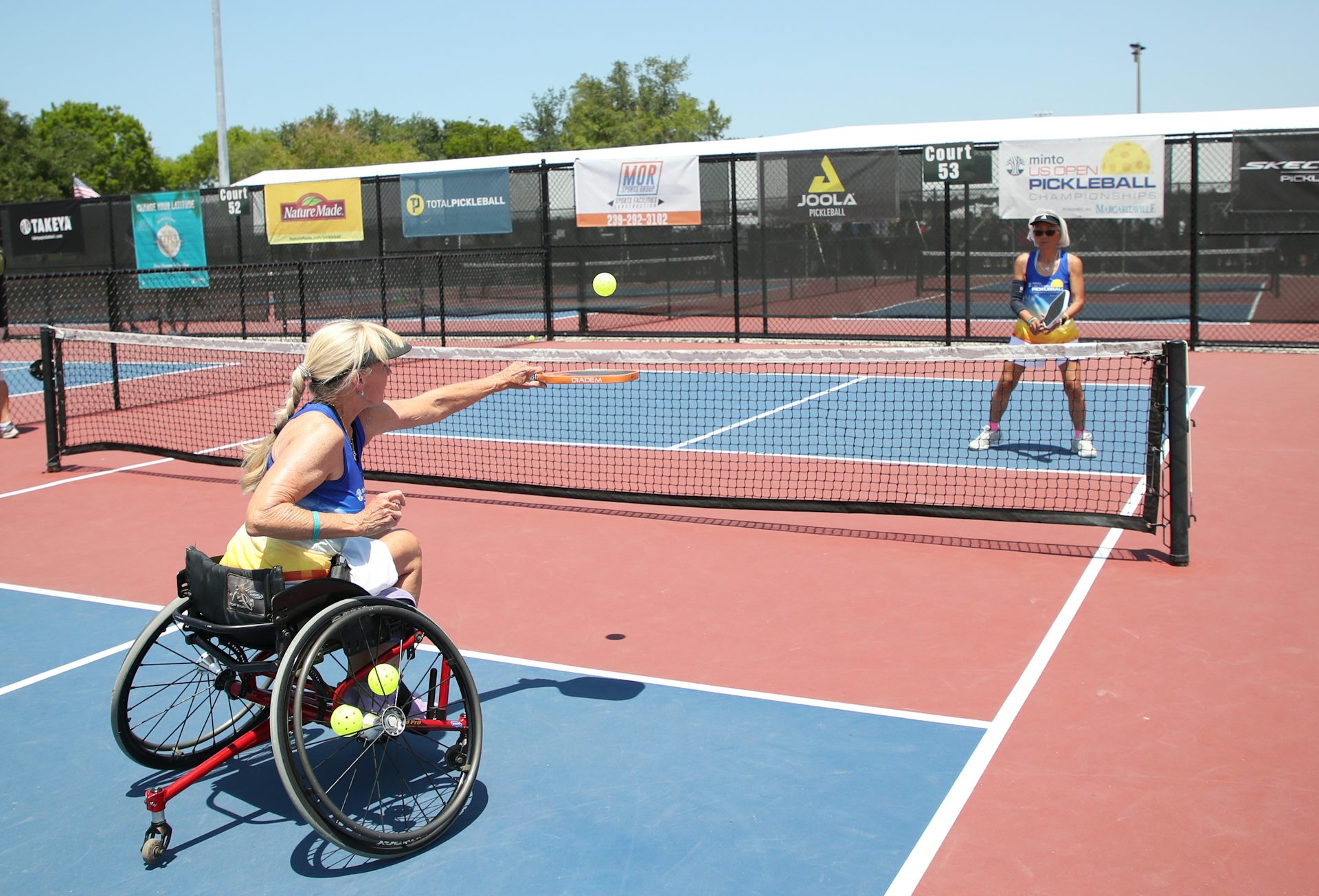 Two women play pickleball. One is in a wheelchair